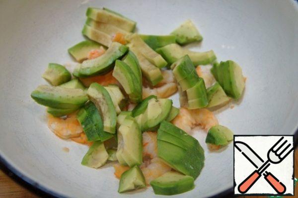Cut the avocado lengthwise into 4 pieces, remove the stone, peel and cut crosswise into slices. Add to the shrimp.