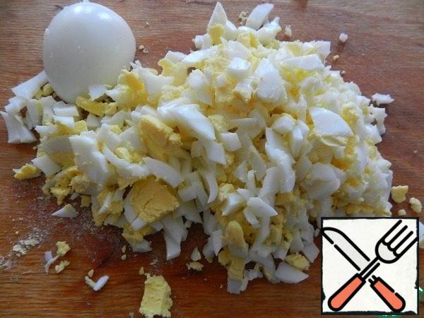 Finely chop the eggs. Also in a bowl, mix with mayonnaise. Place on top of the corn. We put the salad in the refrigerator, but for now we will deal with crackers.