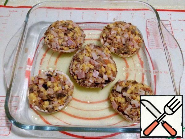 Put the filling on the mushroom caps, put in a baking dish, pour 2 tablespoons of water on the bottom, cover with foil and put in the oven 170°C for 5-6 minutes. Put the glass mold in a warm oven and cook for 10 minutes.