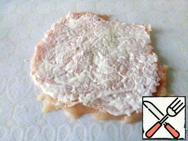 Cut the chicken breast not completely along the entire length and unfold it like a book. Lightly beat off the flat side of the hammer, season with salt and mayonnaise. You can replace it with yogurt or sour cream.