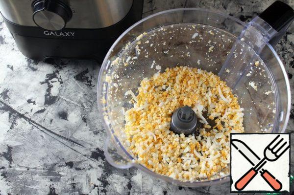 Boil the eggs and let them cool.
Grind in a combine with a "grater" attachment.
Add to apples and onions.