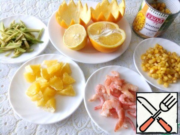 Peel half of the orange from the film and cut into pieces. Cut the avocado into strips and pour over the lemon juice. Pour boiling water over the shrimp for three minutes, drain.