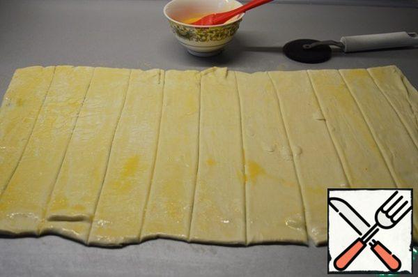 Cut the dough into 3 cm strips. Coat with the egg.