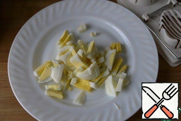 We collect the salad. I took a split form with a diameter of 11 cm, this is for 2 servings.
We cut eggs, it is convenient to use an egg cutter.
