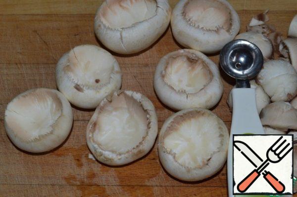 Remove the legs and part of the pulp from the mushrooms (it is convenient to use a noisette, but you can also use a spoon). Do not use the legs, and chop the pulp with a knife.