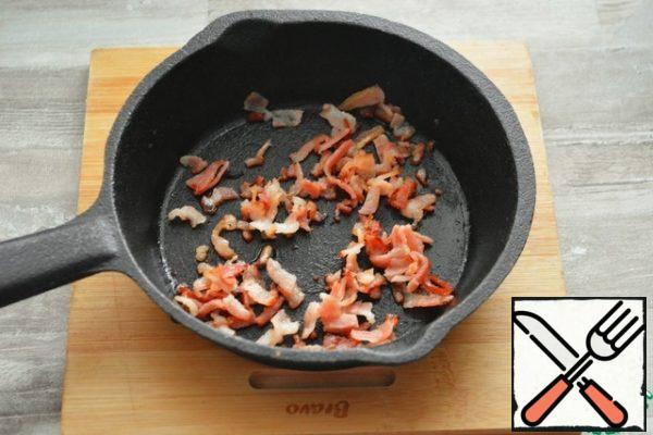 Cut a couple of strips of raw bacon finely and fry in a dry pan until lightly crunched, cool.