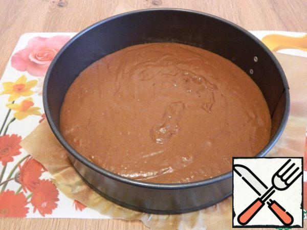 In a form with a diameter of 24 cm, pour the dough, it itself spreads well. The form is pre-covered with paper.