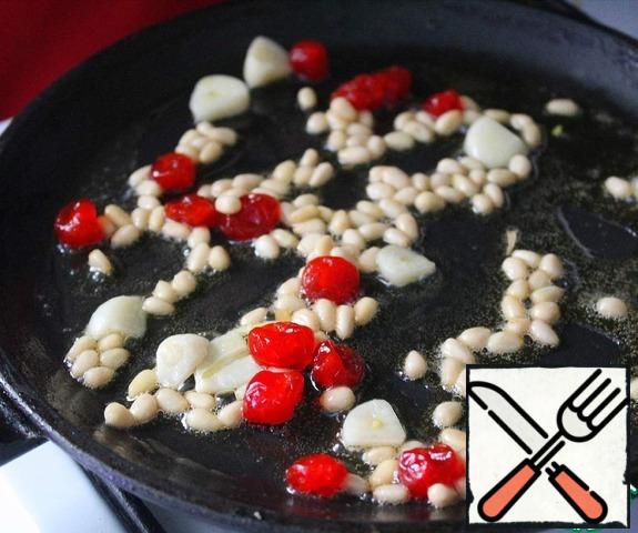 In a frying pan, put a piece of butter, cut the garlic and add it to the same place. Pour the cherries and pine nuts into the pan, fry over medium heat for a few minutes, until the nuts are browned.