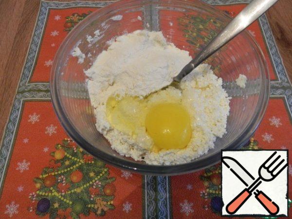 To the cottage cheese, add the egg, flour 2 tablespoons and mix.