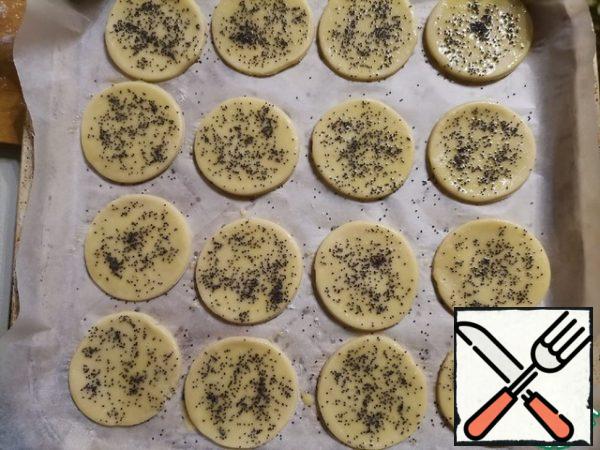 Cover the baking sheet with parchment and lay out the circles. Brush them with egg yolk and sprinkle with poppy seeds.