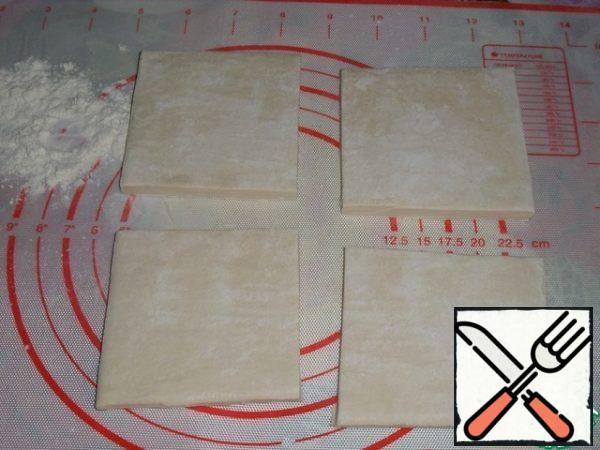 We divide the layer of puff pastry into 4 equal parts.