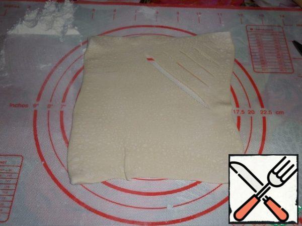 Roll out each part of the dough with a rolling pin in the form of a square. In the upper part of the square we make diagonal cuts using a knife.