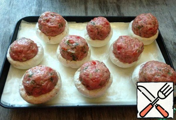 From the resulting mass, form meatballs and put them on top of the mushroom caps. Transfer the stuffed mushrooms to a covered and greased baking sheet. Cook in the oven, preheated to 180 degrees, 25-30 minutes.