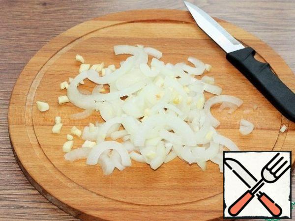 
Chop the peeled onion and garlic: onion in half rings and finely garlic. Fry onion and garlic in heated sunflower oil until transparent.