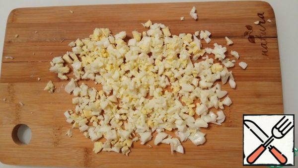 Eggs are cut into medium-sized cubes. Cheese three on a large grater. Add everything to the salad bowl.
