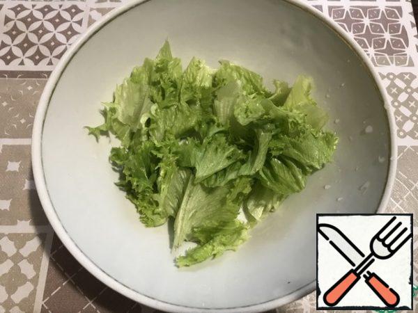 Lettuce leaves are randomly torn by hand and placed on the bottom of the salad bowl .