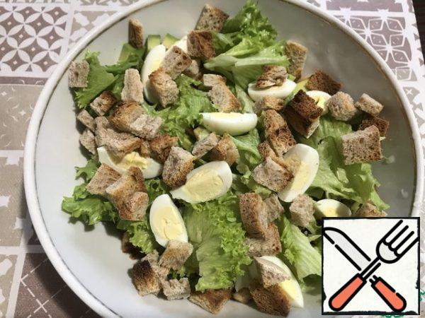 Again, we tear the salad and put it in a salad bowl.
Top with crackers and quarters of quail eggs.