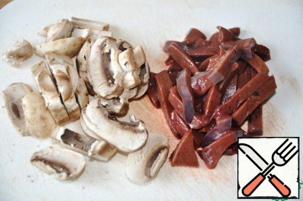 To prepare this salad, you can take both beef and chicken liver. We remove the film from the liver, dry it with a paper towel, it is easier to work with the frozen product. Cut the beef liver into strips. If the liver is chicken, then cut the pieces in half.
Mushrooms are washed, dried and cut into plates.