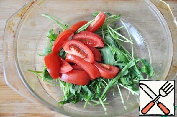 In a plate, put the washed dried arugula.
Add the tomatoes cut into segments.
