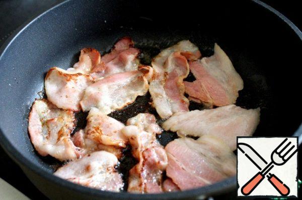 Cut a slice of bacon in half and fry, in a dry well-heated frying pan, until golden brown.