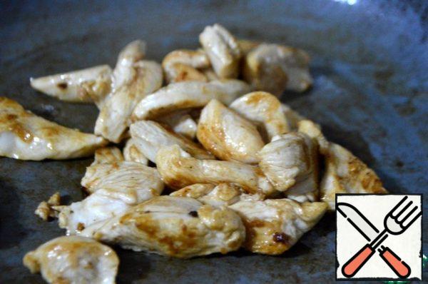 Cut the chicken fillet into thin strips across the fibers, add a second spoonful of oil and fry over high heat for 4-5 minutes until golden brown.