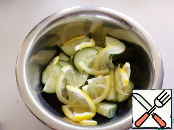 Cut cucumbers into half rings, lemon into thin, thin slices.