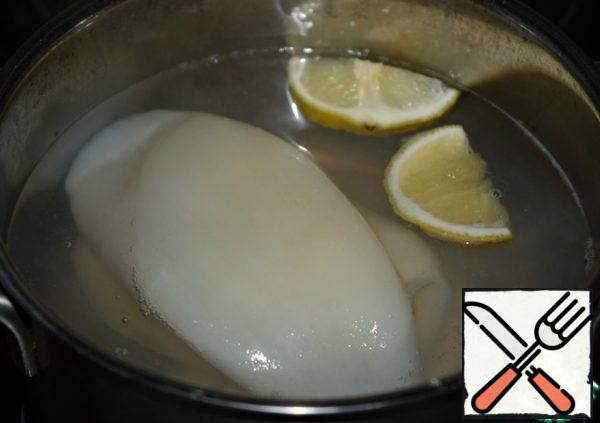 Boil the squid (defrost beforehand and peel) in boiling well-salted water with a slice of lemon for a couple of minutes. Cool down.