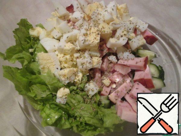 Wash the lettuce leaves, dry them, cut them coarsely or tear them with your hands. Put all the ingredients in a salad bowl, add salt, and sprinkle with oregano. For the dressing, mix the olive oil, balsamic vinegar and garlic. Pour the dressing over the salad.