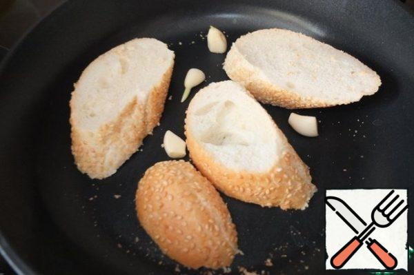 Cut the baguette into slices. Each slice on one side is spread with a thin layer of butter. Put the garlic in a frying pan, then the baguette slices with the greased side down. Fry until golden brown on both sides. The garlic will leave a light, barely perceptible aroma.