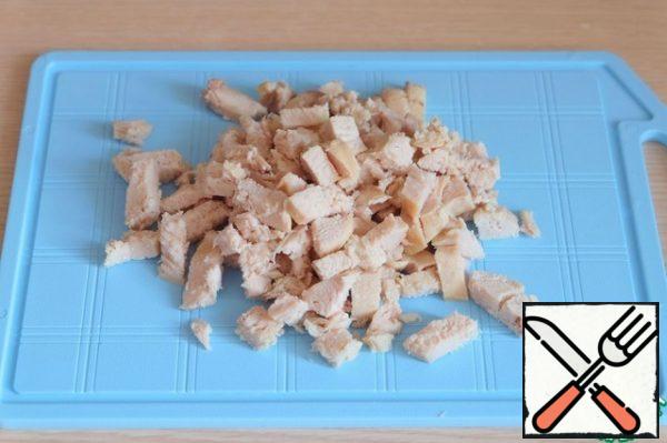 Boil chicken fillet, cut into cubes.