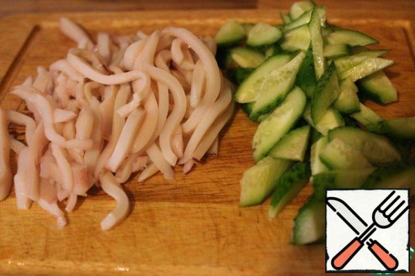 Prepare the squid. We will prepare them in a "short" way, which involves pouring boiling water over them. Pour boiling water over the squid, let it stand for half a minute, remove the skin and remove the remaining chord. Rinse with cold water. Again pour the squid with boiling water, leave for a minute. Again, rinse with cold water and repeat the procedure again - pour boiling water, leave for a minute and rinse. Now quickly cut them into strips along with cucumbers.