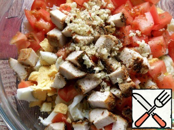 Chicken fillet and tomatoes are also cut into cubes. Finely chop the garlic and add it to the salad along with the black pepper.