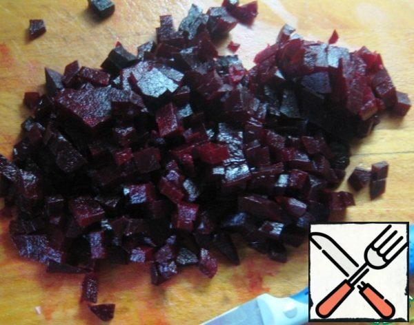 Peel the pre-boiled beets and cut them into small cubes.
Combine all the ingredients of the salad in a convenient mixing bowl, season with black pepper and salt to taste.