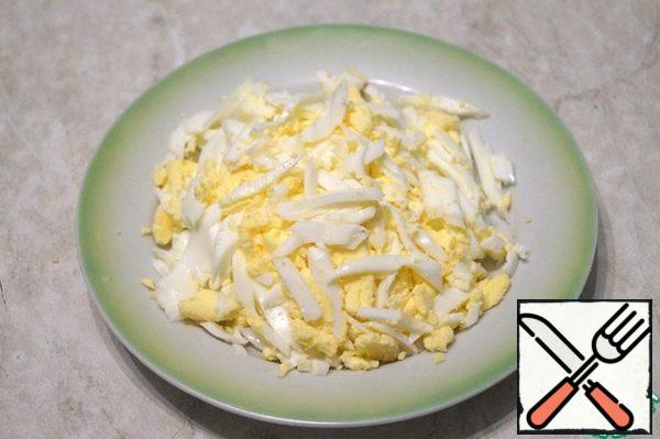 Boil the eggs, peel them from the shell, and cut them into strips.