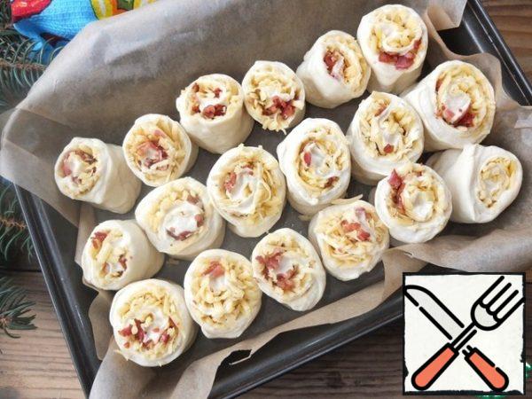 
Cover the form with baking paper.
Cut the resulting rolls into pieces of 5-7 cm.
We put them with a cut upwards into the prepared form at some distance from each other.