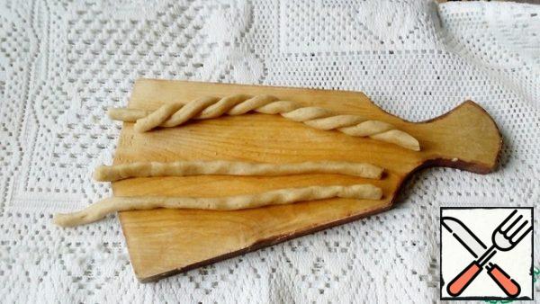 We form "handles" from the remaining dough. To do this, we roll out thin flagella and connect them in pairs.