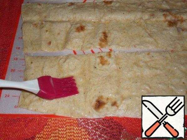 
Lay out strips of pita bread on the working surface. Grease each strip with a beaten egg, salt and pepper. We leave for a couple of minutes.