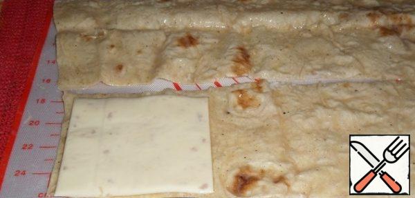 
Put a slice of cheese on each strip of pita bread.