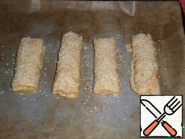 We spread the rolls on a baking sheet. Sprinkle with sesame seeds. Place the baking sheet in a preheated oven.