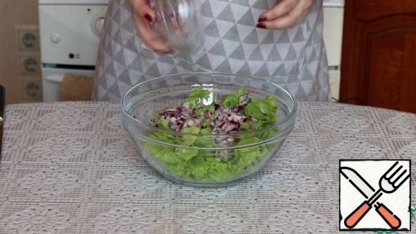 We collect the salad. In a deep bowl, put the lettuce leaves, chopped red onion.