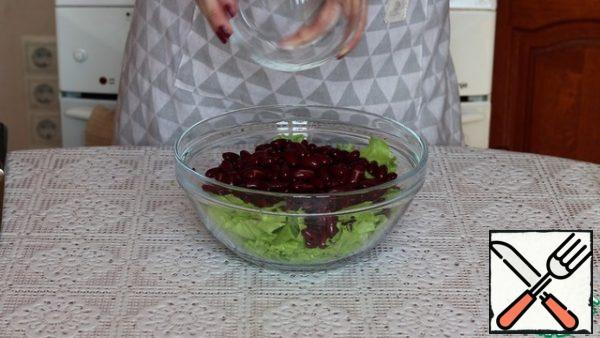 Red canned beans are drained from the jar and washed under running water. Let the water drain and pour it into a salad bowl.