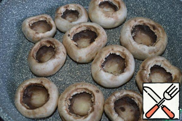 Remove the legs from the mushrooms and place them in a preheated dry frying pan.
Fry on one side.
Flip to stack the released juice.
