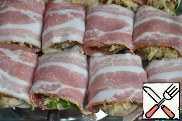 Wrap each cap with a strip of bacon, put it in a baking dish and send it to a preheated 180*C oven for 15 minutes.