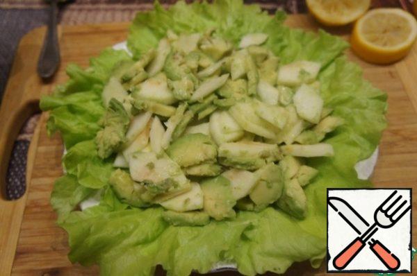 Cut the avocado in half, remove the bone, then carefully remove the pulp with a tablespoon, cut it into slices across the pieces. Sprinkle with a second spoonful of lemon juice. Mix very gently.
Spread the avocado slices on the lettuce leaves.