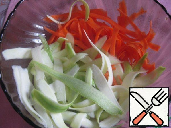 The zucchini is first peeled with a vegetable peeler, and then cut into ribbons.