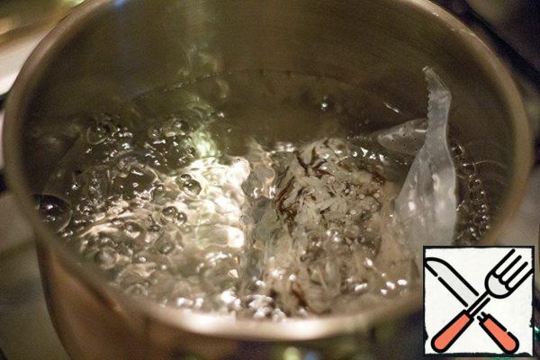 In salted boiling water, lower a bag of rice. Simmer for 15 minutes. At the end of cooking, take out the bag and let the water drain.