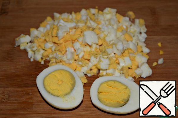 Boiled eggs cool slightly, peel and immediately finely chop. (hot)