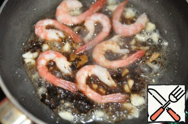 Put the shrimp in the garlic oil, fry for a few seconds and pour 1 tablespoon of soy sauce, mix. Pour the lemon juice over the shrimp and remove from the stove.