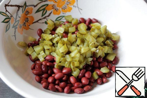 Add the pickled cucumbers to the beans, cut into small cubes (they should be the size of chopped nuts).