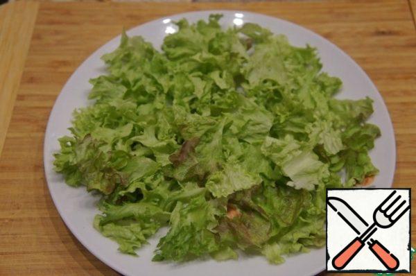 Pick the lettuce leaves with your hands, put most of them on a flat dish, covering the entire bottom. Pour the rest into a deep bowl.